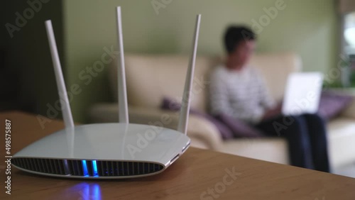 Selective focus at router. Internet router on working table with blurred man using tablet at the background. Fast and high speed internet connection from fiber line with LAN cable connection.