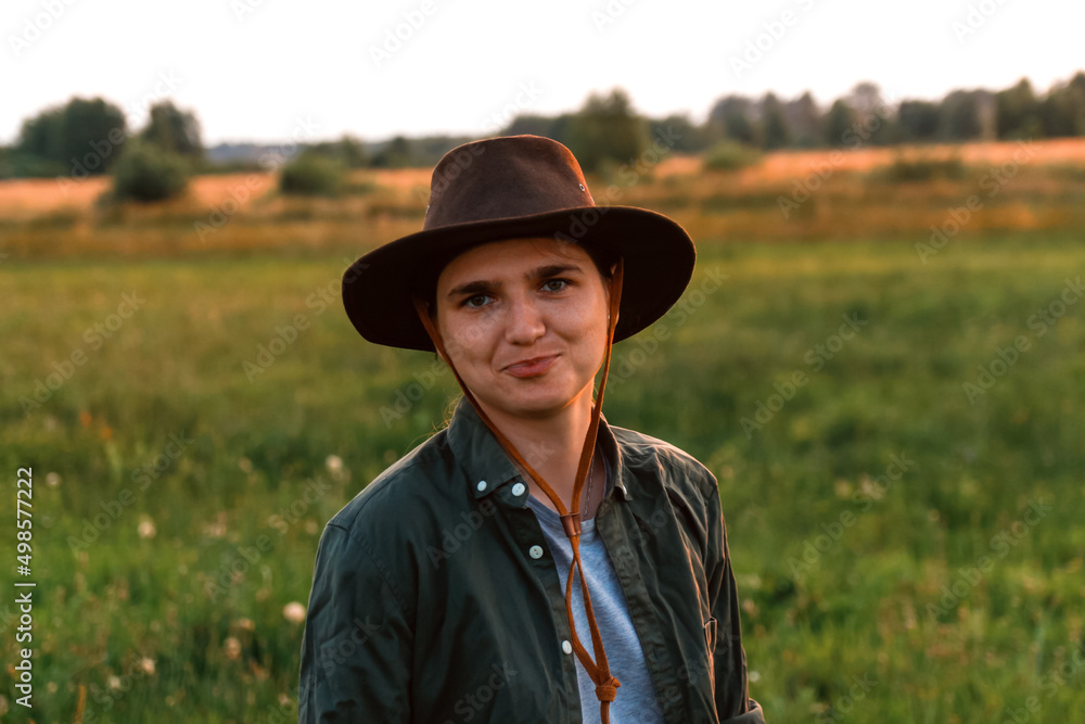 Defocus young woman in cowboy hat. Girl in a cowboy hat in a field. Sunset. Nature background. Closeup portrait caucasian girl. Out of focus