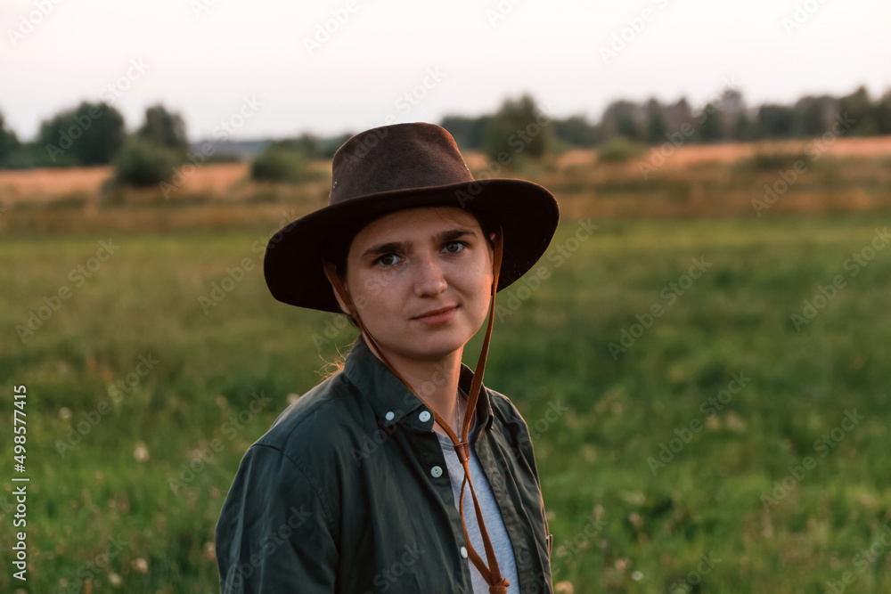 Defocus young woman in cowboy hat. Girl in a cowboy hat in a field. Sunset. Nature background. Closeup portrait caucasian girl smiling. Summertime. Fashion. Out of focus Defocus young woman in cowboy hat. Girl in a cowboy hat in a field. Sunset. Nature background. Closeup portrait caucasian girl smiling. Summertime. Fashion. Out of focus