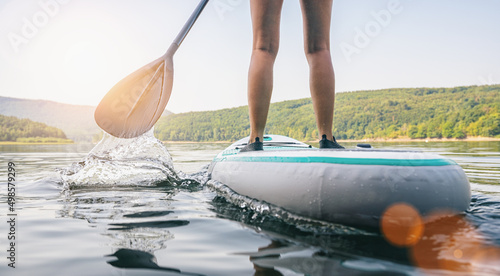 Stand up paddle boarding on a quiet lake at summer, close-up of 