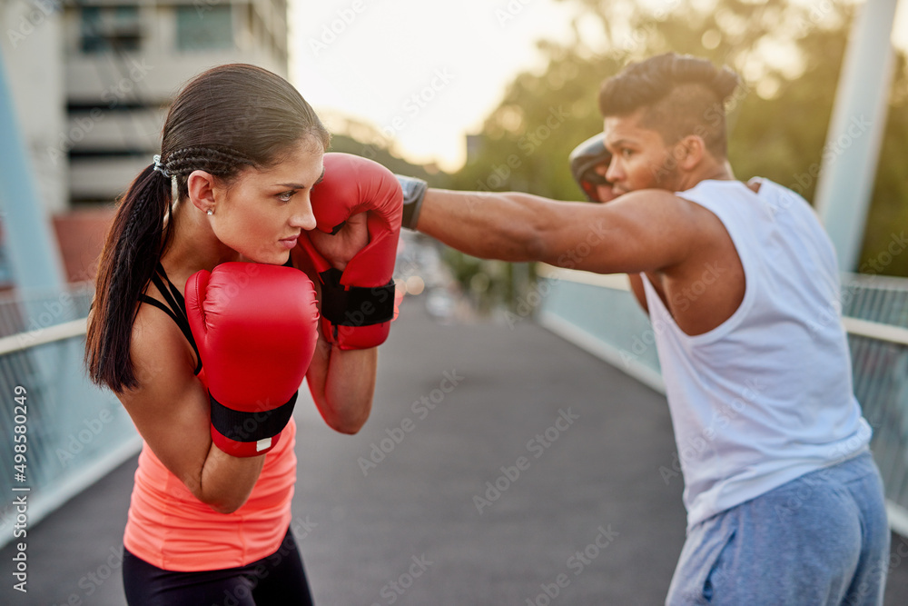 Bob and weave. Shot of a young couple going through some kickboxing routines outdoors on a bridge.