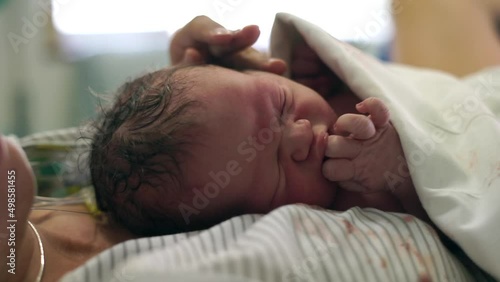 The newborn baby boy calmly lying on his mother's chest right after birth