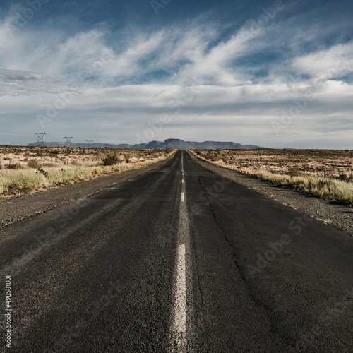 Canvastavla Asphalt road through arid lands on a blue cloudy sky background