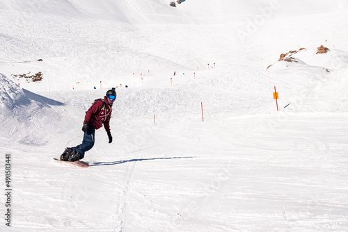 St. Anton am Arlberg. March 10, 2022. Young snowboarder sliding down slope on snow covered mountain at ski resort during beautiful sunny day, Male snowboarder riding snowboard in mountain