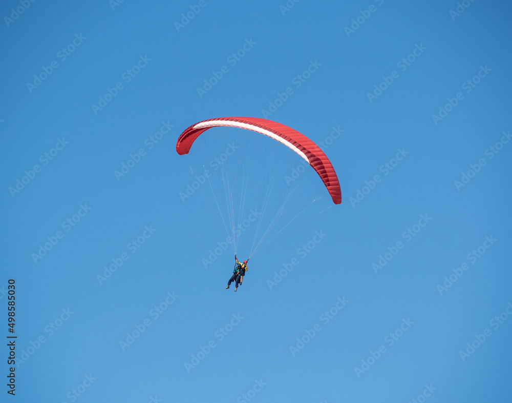 People in tandem paragliding at clear blue sky background People in tandem paragliding at clear blue sky background