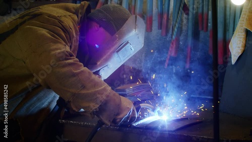 A man welds plates for body armor from springs. homemade armor plate. Factory worker welds metal. The man is welding. Welding with argon or electrode, using a welding machine. Sparks and flashes fly