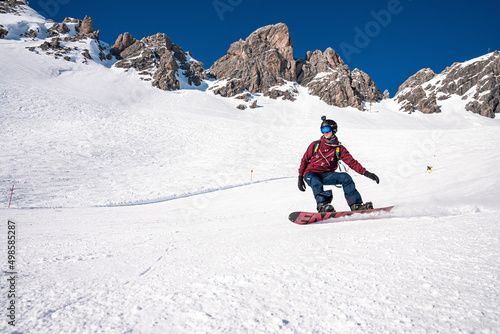 St. Anton am Arlberg. March 10, 2022. Young snowboarder sliding down slope on snow covered mountain at ski resort during beautiful sunny day, Male snowboarder riding snowboard in mountain