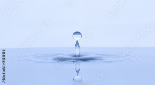 Splash and a ball of water on a blue background. Reflection on the surface of the water.