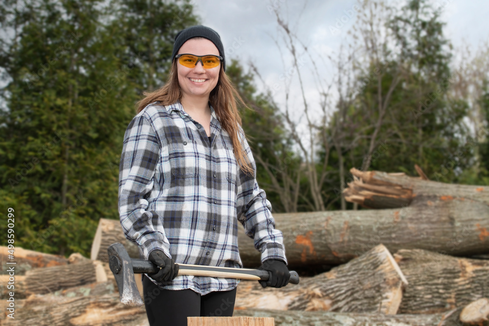 Young woman splitting firewood with a maul