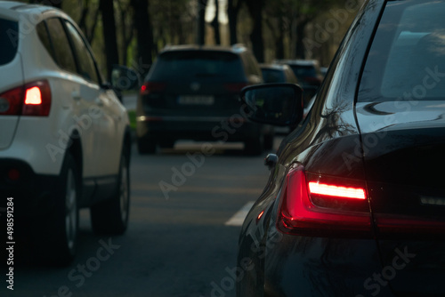 Standing in traffic and waiting. Close up view with rear red lights of the cars. Transportation industry.