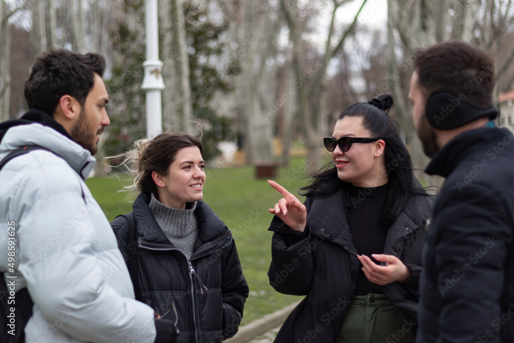 Four people talkin with eachothers. They are having fun, laughing at park. Four people talkin with eachothers. They are having fun, laughing at park.
