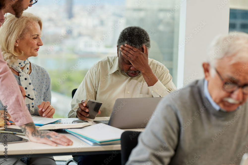 A senior african man having trouble learning the use of the internet on the course for senior people in the classroom. A senior african man having trouble learning the use of the internet on the course for senior people in the classroom.
