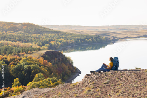 A woman with a backpack on the background of the lake and forest.