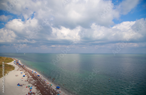 Aerial view of the beautiful sandy beach on the coast gleaming under the cloudy blue sky photo