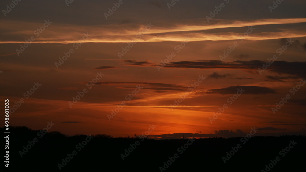 Romantischer Sonnenuntergang im Norden mit Wolken und orangenen und roten Farben