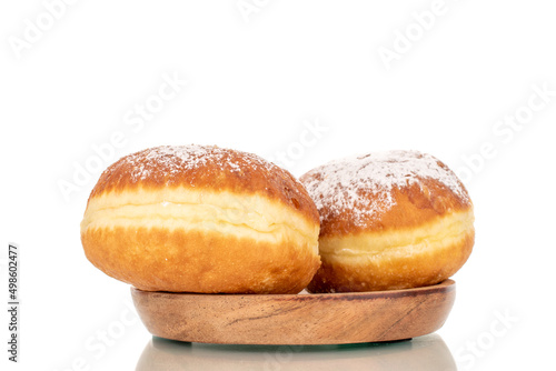 Two sweet donuts stuffed with jam on a wooden saucer, close-up, isolated on a white background.