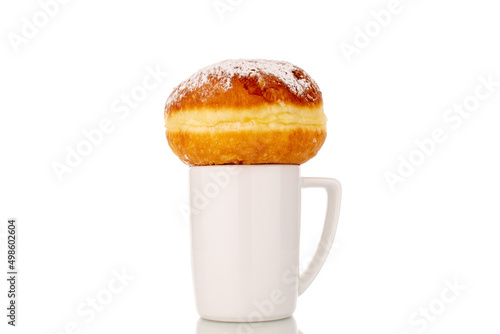 One sweet donut stuffed with jam with a white ceramic cup, close-up, isolated on a white background.