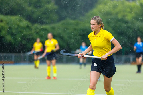 Young teenage girl running on the pitch during the field hockey game in rain