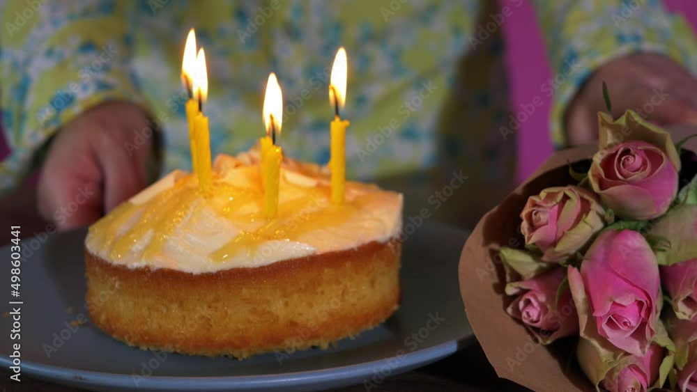 Woman places pink roses next to birthday cake Woman places pink roses next to birthday cake