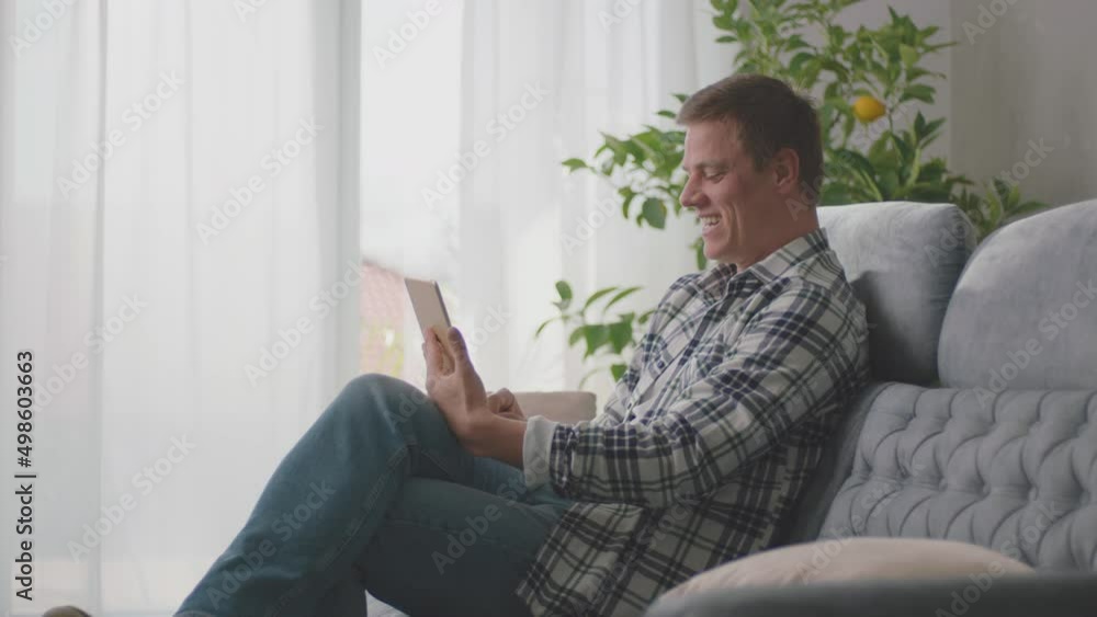 A young man sitting on a couch, doing vedio call with his colleague, discussing about project, official conversation with boss