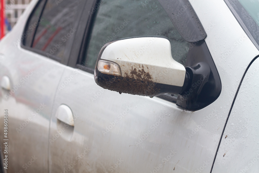 The side mirror of a white car is covered with dirt in rainy weather in spring or summer The side mirror of a white car is covered with dirt in rainy weather in spring or summer