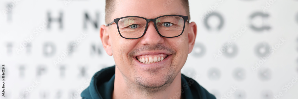 Portrait of smiling man with glasses on background of table for vision test Portrait of smiling man with glasses on background of table for vision test