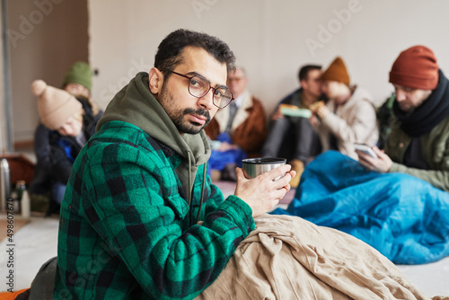 Portrait of refugee hiding in shelter during war or crisis and holding hot drink, copy space photo