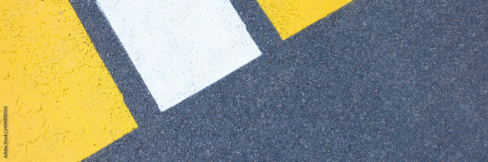 Fototapeta premium Closeup of yellow and white stripes on gray asphalt background