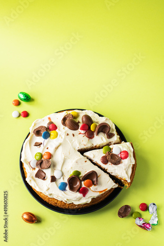 Easter cake with chocolate eggs, candies and cream cheese frosting. Top view and copy space.