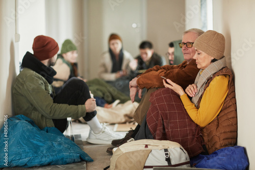 Bilde på lerret Side view portrait of Caucasian refugees sitting on floor in shelter covered wit