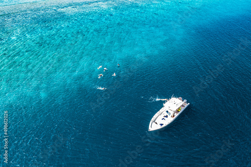 Beautiful turquoise ocean water and boat, view aerial drone seascape. Tropical sea waves, amazing aerial coral reef, lagoon. People recreational outdoor activity, swimming, snorkeling, diving tourism © icemanphotos