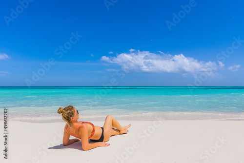 Woman relaxing on the beach. Sexy bikini body legs, sunglasses woman enjoying paradise tropical beach. Exotic shore, sea water as freedom concept. Beautiful carefree fit body girl on travel vacation © icemanphotos