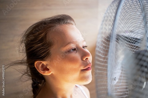 a little girl rejoices in the breeze from a large fan in the heat, her hair develops