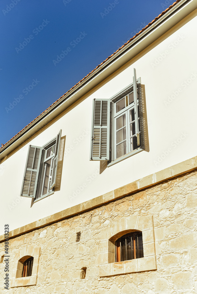 windows with shutters on an old building, the wall of the building and the blue sky