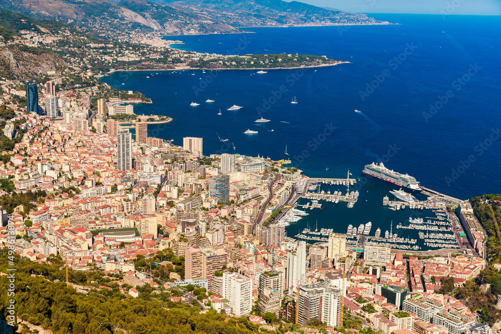 Aerial view of port Hercules of Monaco at sunset, Monte-Carlo, huge cruise ship is moored in marina, view of city life from La Turbie mountain, a lot of mega yachts and boats