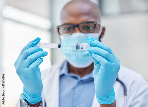 A cure has finally been found. Shot of a young doctor using a syringe to extract medication from a vial.