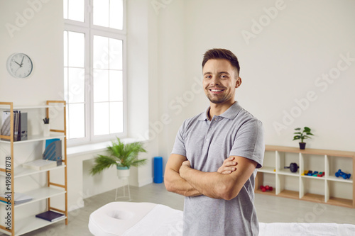 Portrait of happy doctor, physiotherapy expert or massage specialist. Man who works as professional physiotherapist at modern rehabilitation centre standing in office, looking at camera and smiling