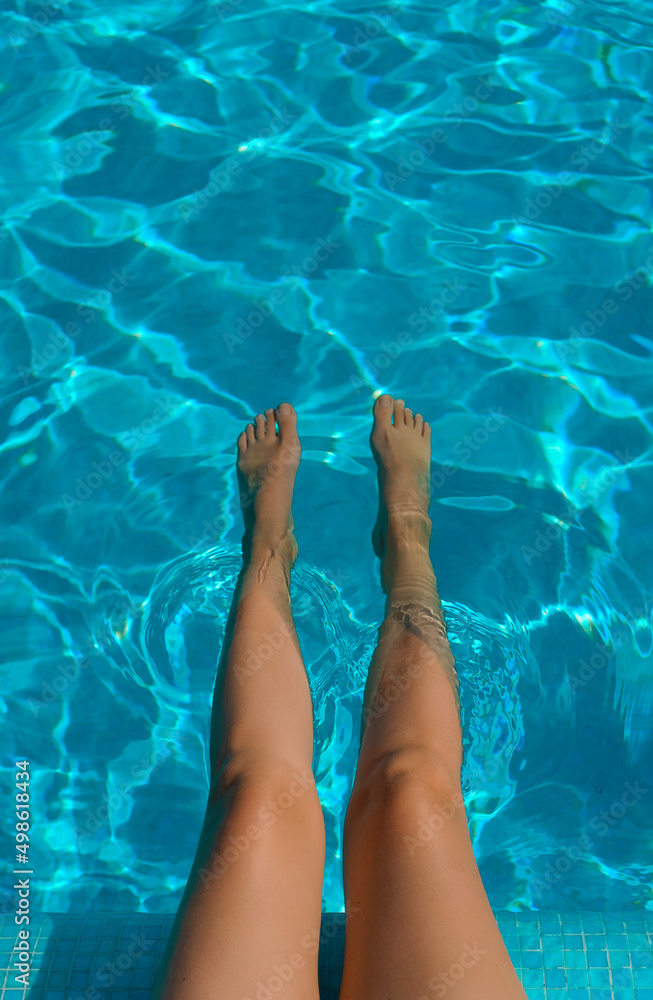 Female legs. Woman sitting near the pool.