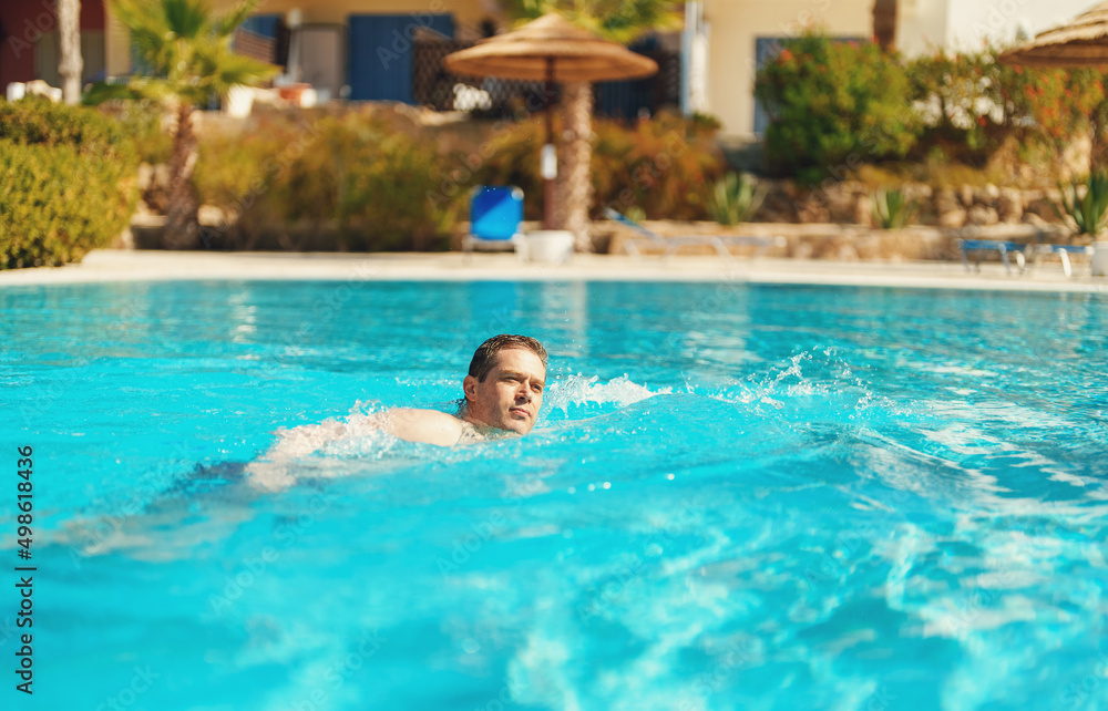 Man swimming in outdoor swimming pool.