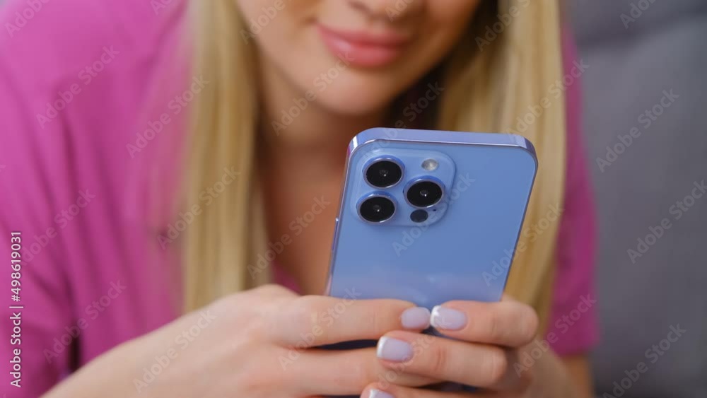 Woman texting on mobile phone. Young female typing a message on modern blue smartphone with triple camera Woman texting on mobile phone. Young female typing a message on modern blue smartphone with triple camera