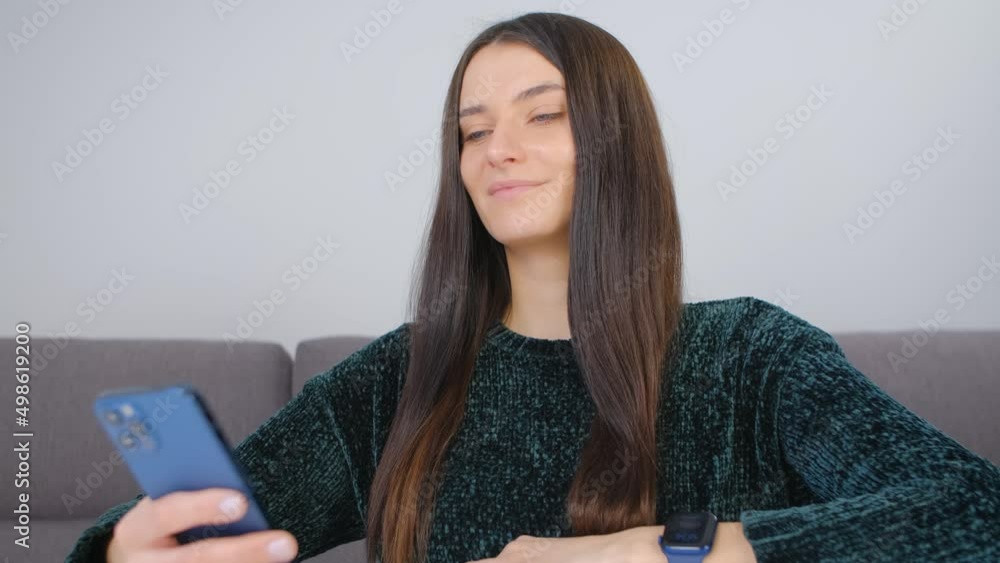Cheerful young woman browsing mobile app on a smart phone at home Cheerful young woman browsing mobile app on a smart phone at home