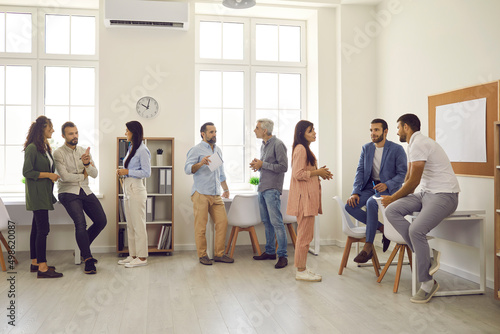 Groups of people gathering in modern spacious office during break at business conference or after company corporate meeting, talking, discussing speakers and making useful contacts for collaboration photo