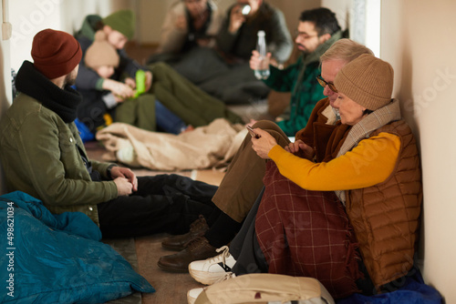 Fotografi Side view portrait of senior refugees hiding in shelter during war or crisis and