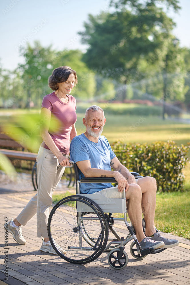 Obraz premium A dark-haired woman carrying her husband in a wheel chair