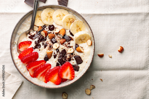 Bowl of millet porridge with frut nuts and dark chocolate photo