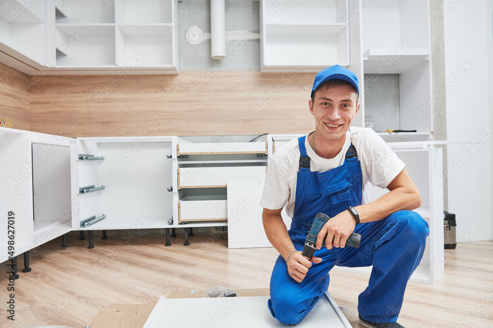 kitchen installation. Worker assembling furniture
