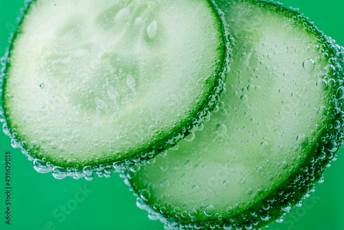 Cucumbers sliced with water bubbles on green background. Macro image, selective focus, abstract food background.