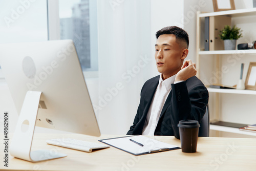 man in a suit glass of coffee sits at a tablein front of a computer technologies