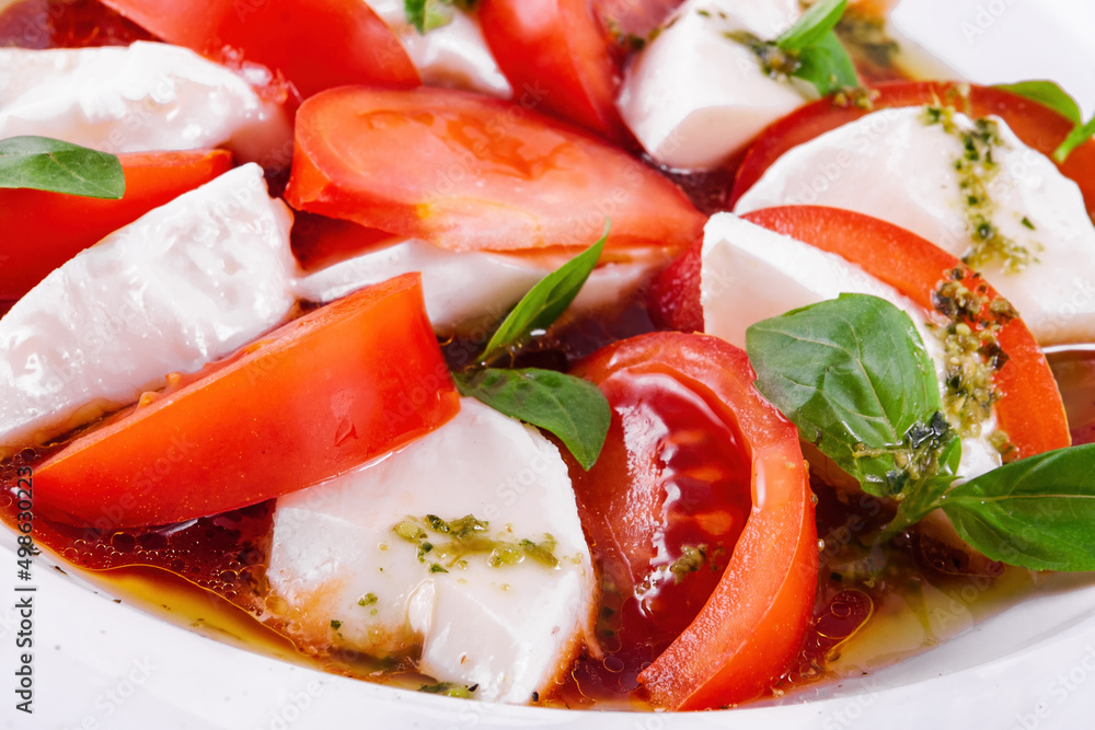 Caprese salad with pesto sauce on a white plate