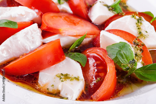 Caprese salad with pesto sauce on a white plate